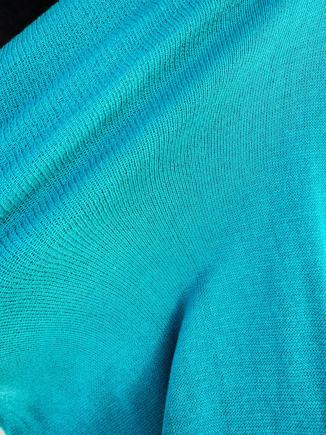 Close view of teal knit opening under tension